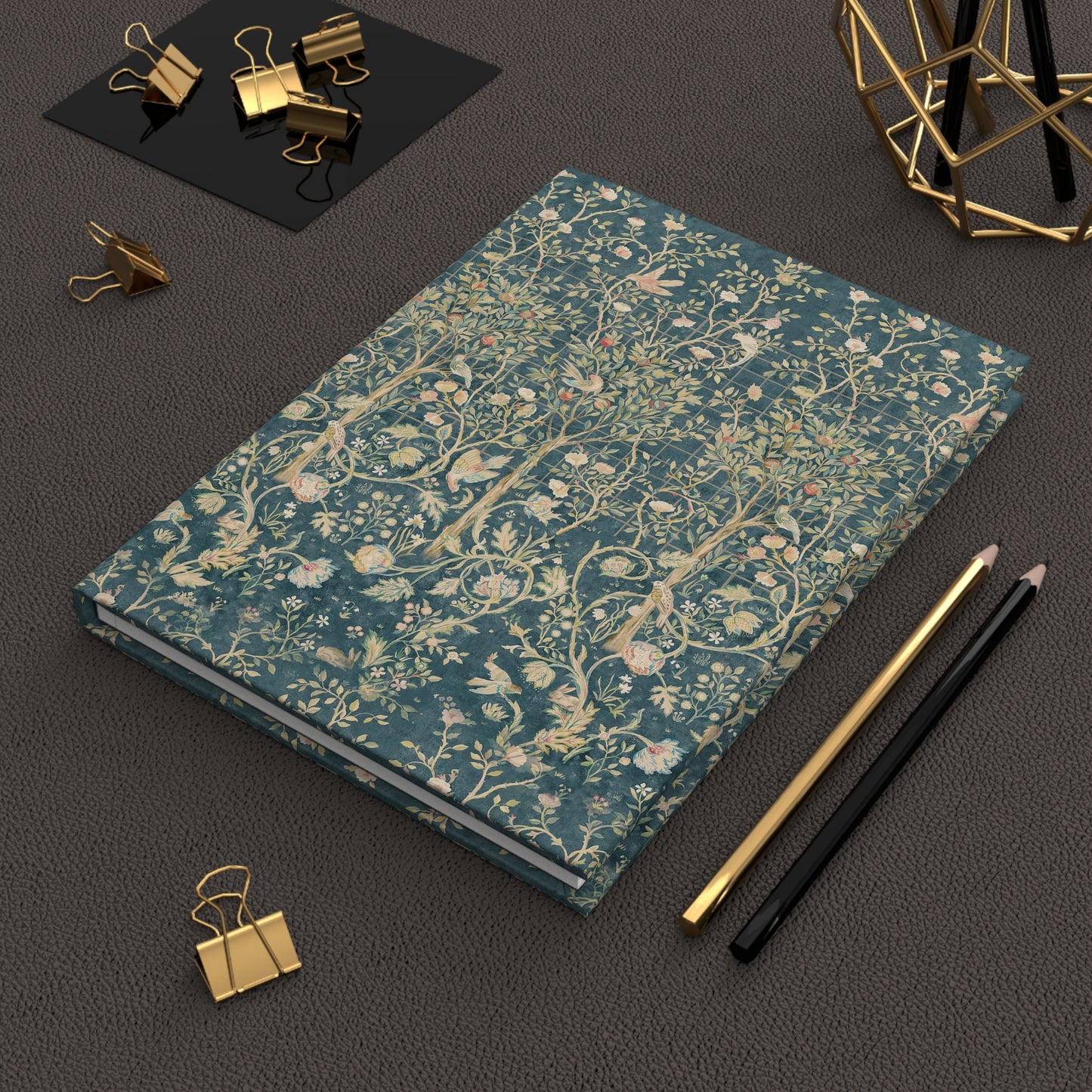 Floral patterned notebook on a dark surface with office supplies