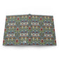 An open book or notebook showing a detailed, repeating Arts and Crafts style floral pattern in blue, green, red, and cream on the pages, photographed against a plain white background.