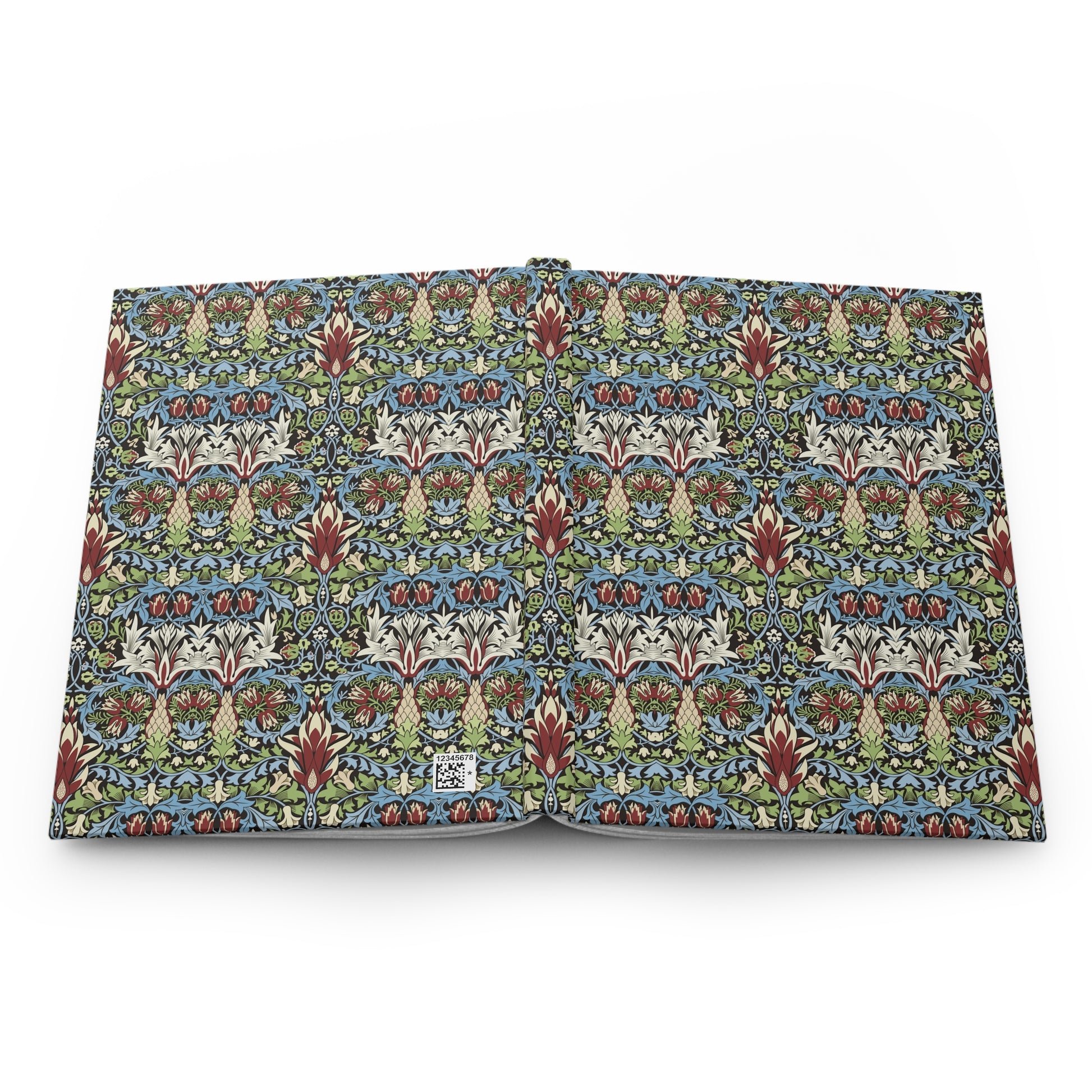 An open book or notebook showing a detailed, repeating Arts and Crafts style floral pattern in blue, green, red, and cream on the pages, photographed against a plain white background.