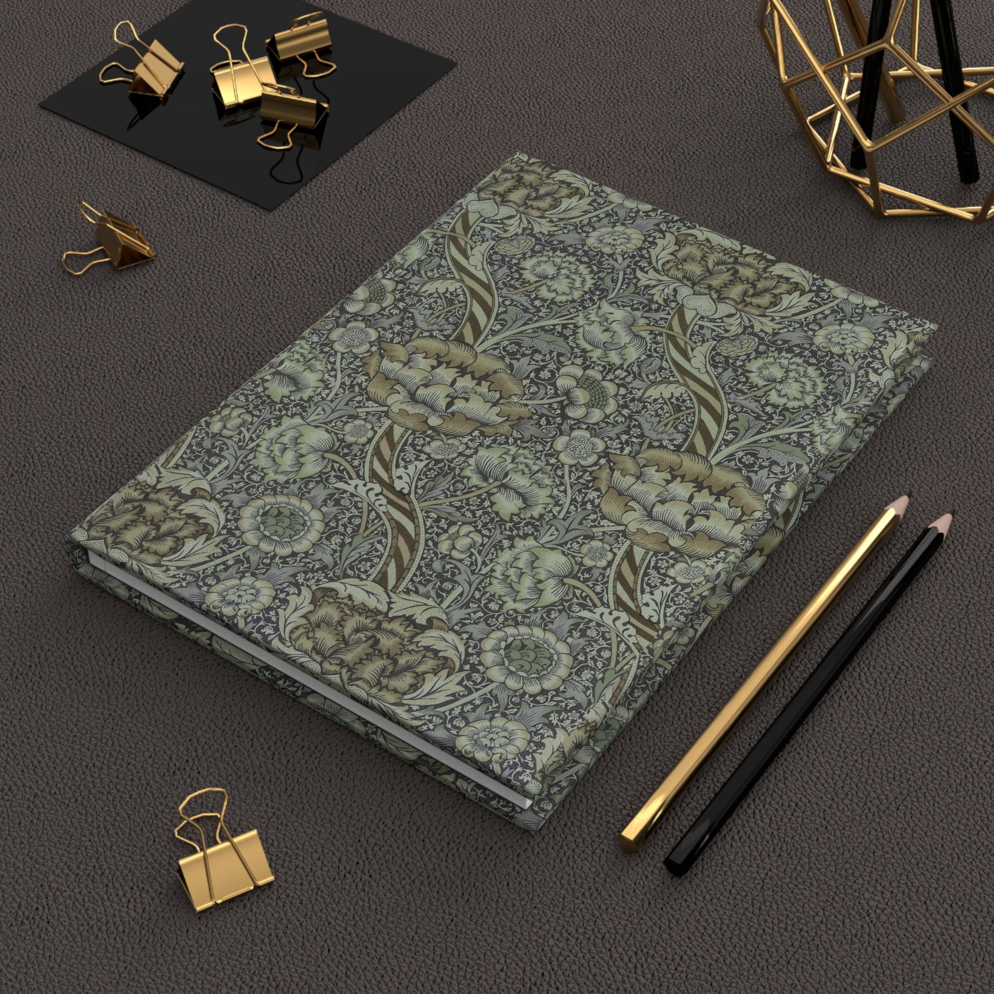 Floral notebook with gold and black office supplies on a dark surface