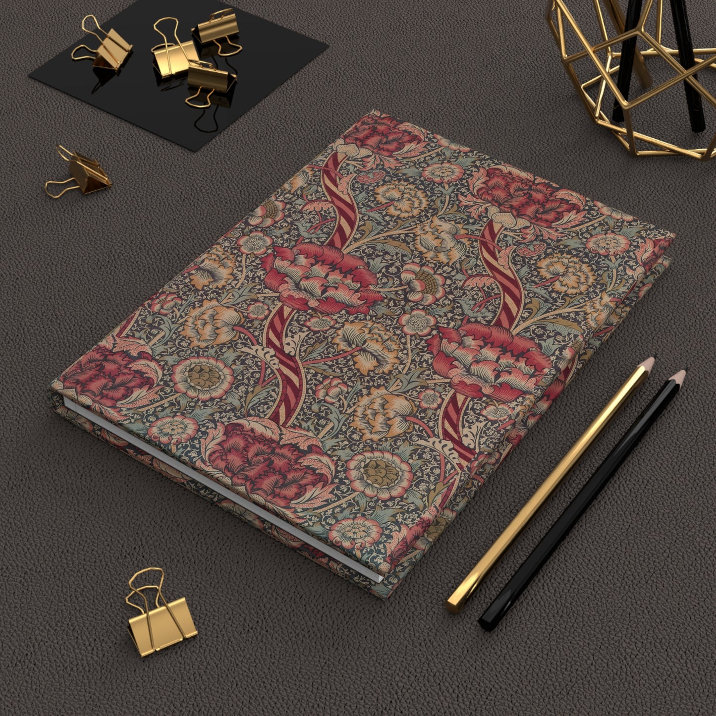 Floral-patterned notebook on a dark surface with office supplies