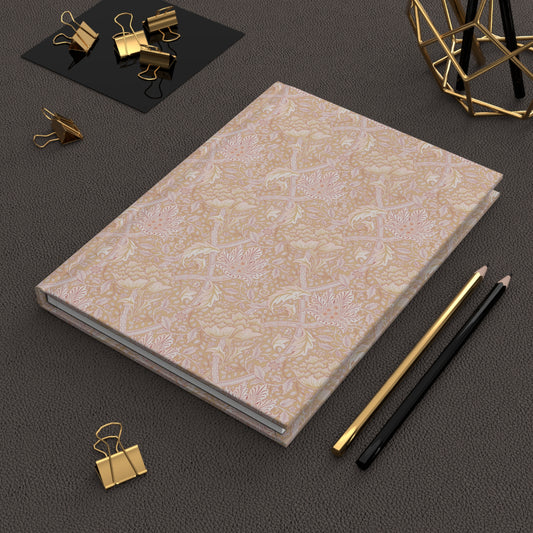 Light orange and pink William Morris & Co notebook with text on a dark surface with office supplies