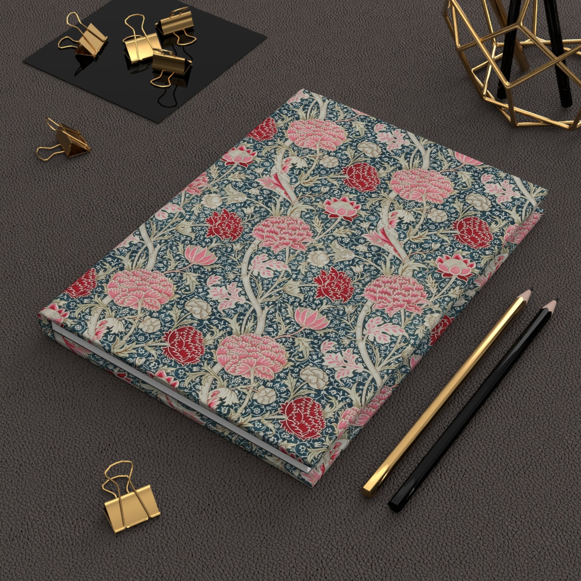 Floral notebook with stationery items on a dark surface