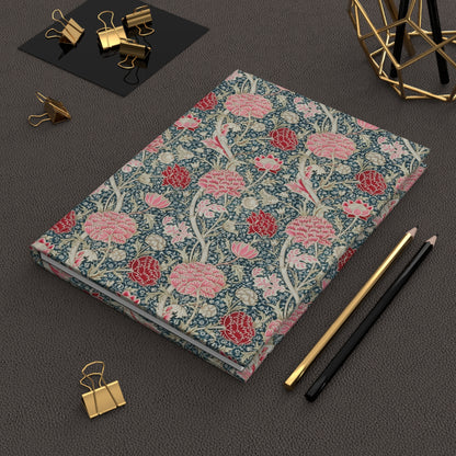 Floral notebook with stationery items on a dark surface