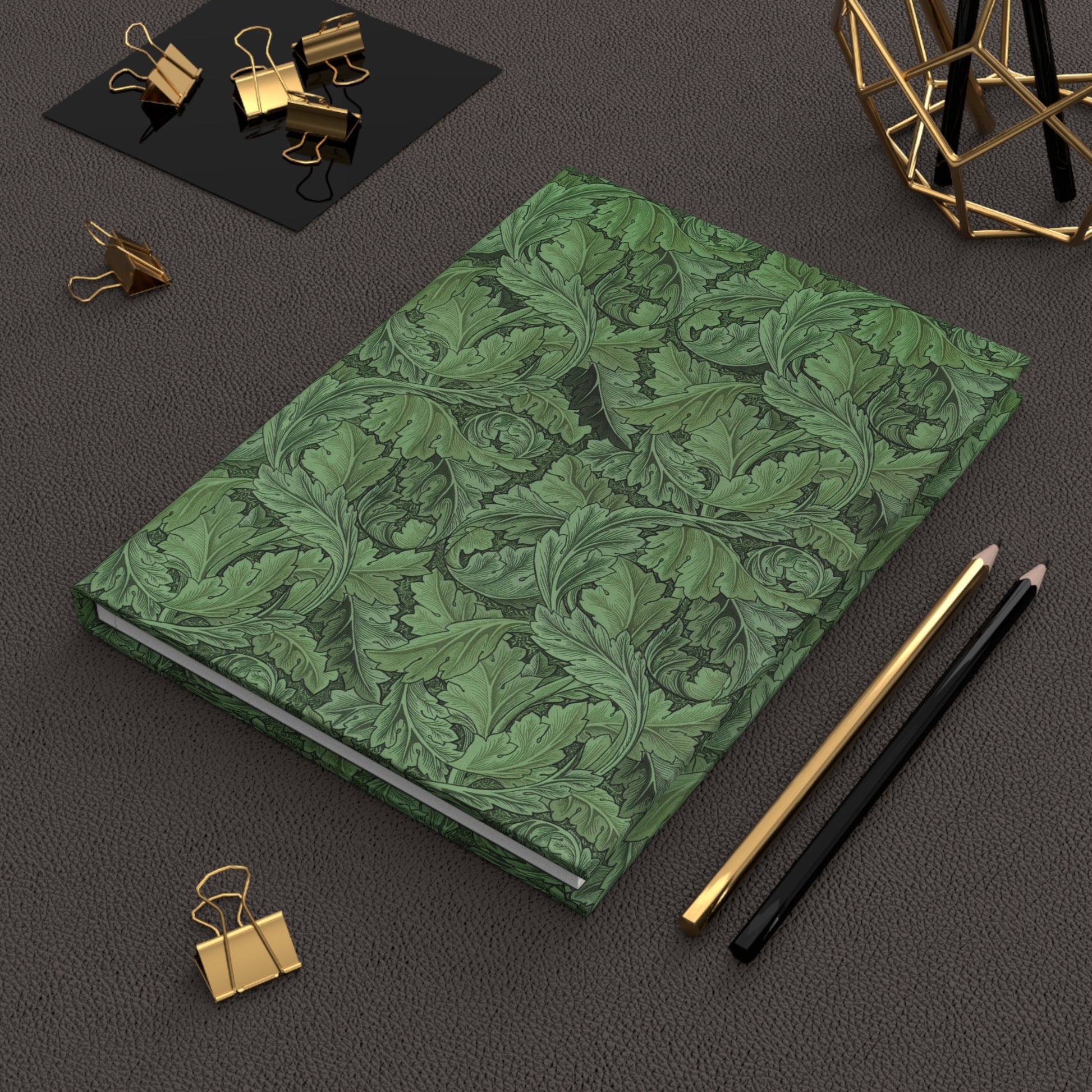 Green patterned notebook on a dark surface with office supplies