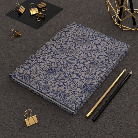 Floral-patterned notebook with gold clips and pencils on a dark surface
