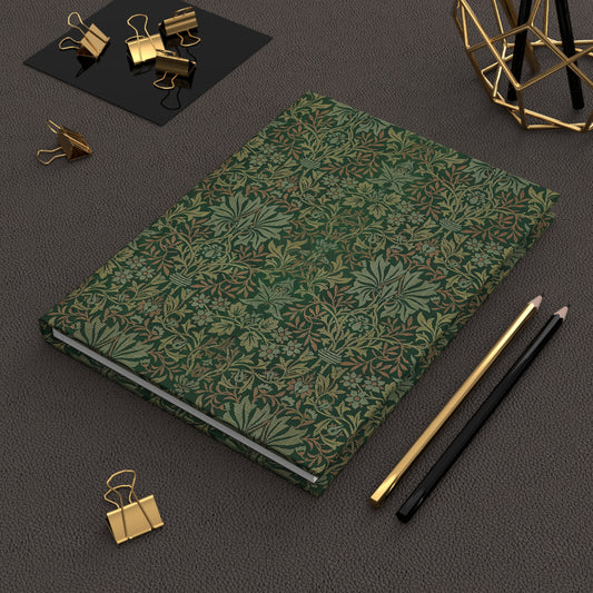 Green patterned notebook with gold and black office supplies on a dark surface