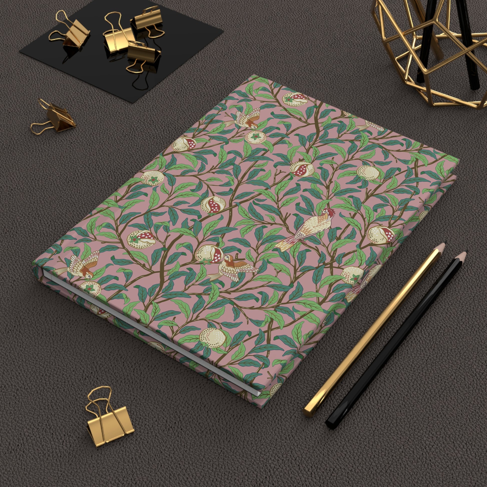 Notebook with a William Morris & Co floral pattern on a dark surface with office supplies.