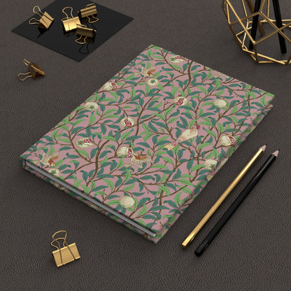 Notebook with a William Morris & Co floral pattern on a dark surface with office supplies.