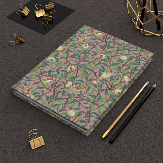 Notebook with a William Morris & Co floral pattern on a dark surface with office supplies.