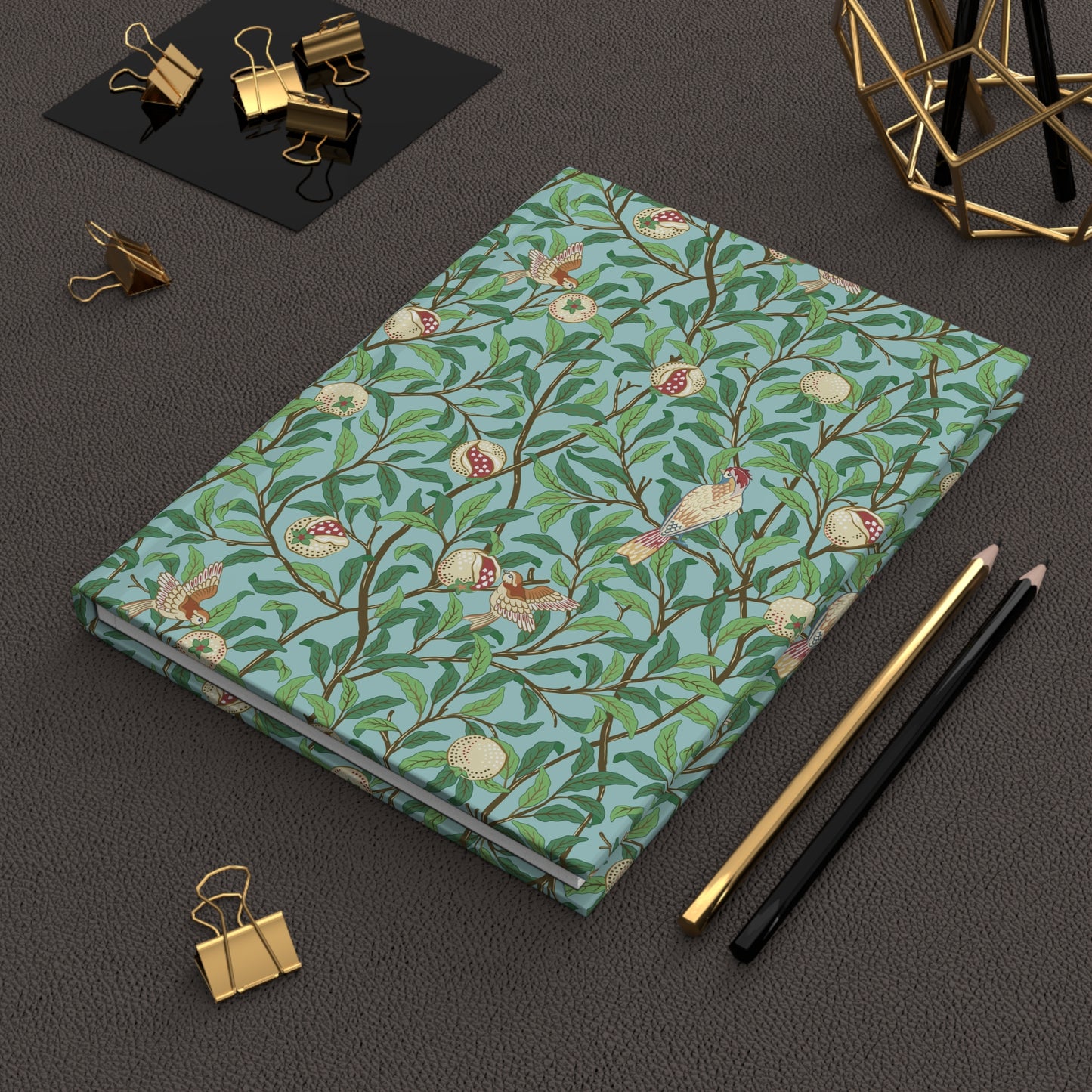 Notebook with floral pattern on a dark surface with office supplies