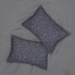 Two square decorative throw pillows with a gray and white floral damask pattern, arranged on a light gray textured fabric background.