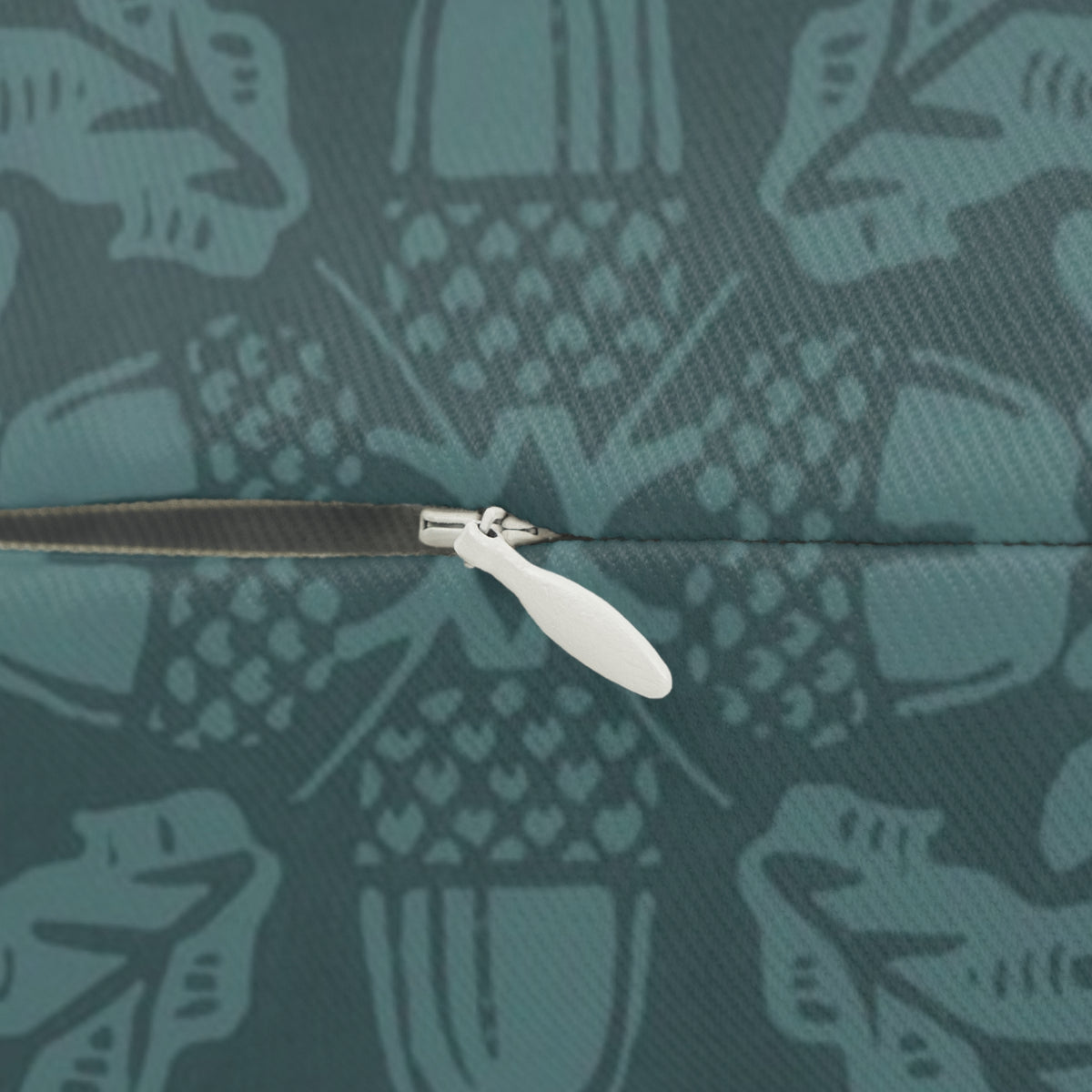 Close-up of a zipper with a white pull tab on a teal fabric background with a repeating light teal pattern.