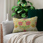 A rectangular lumbar cushion with a floral William Morris & Co pattern featuring honeysuckle designs in shades of pink, green, and yellow, and a concealed beige zipper.