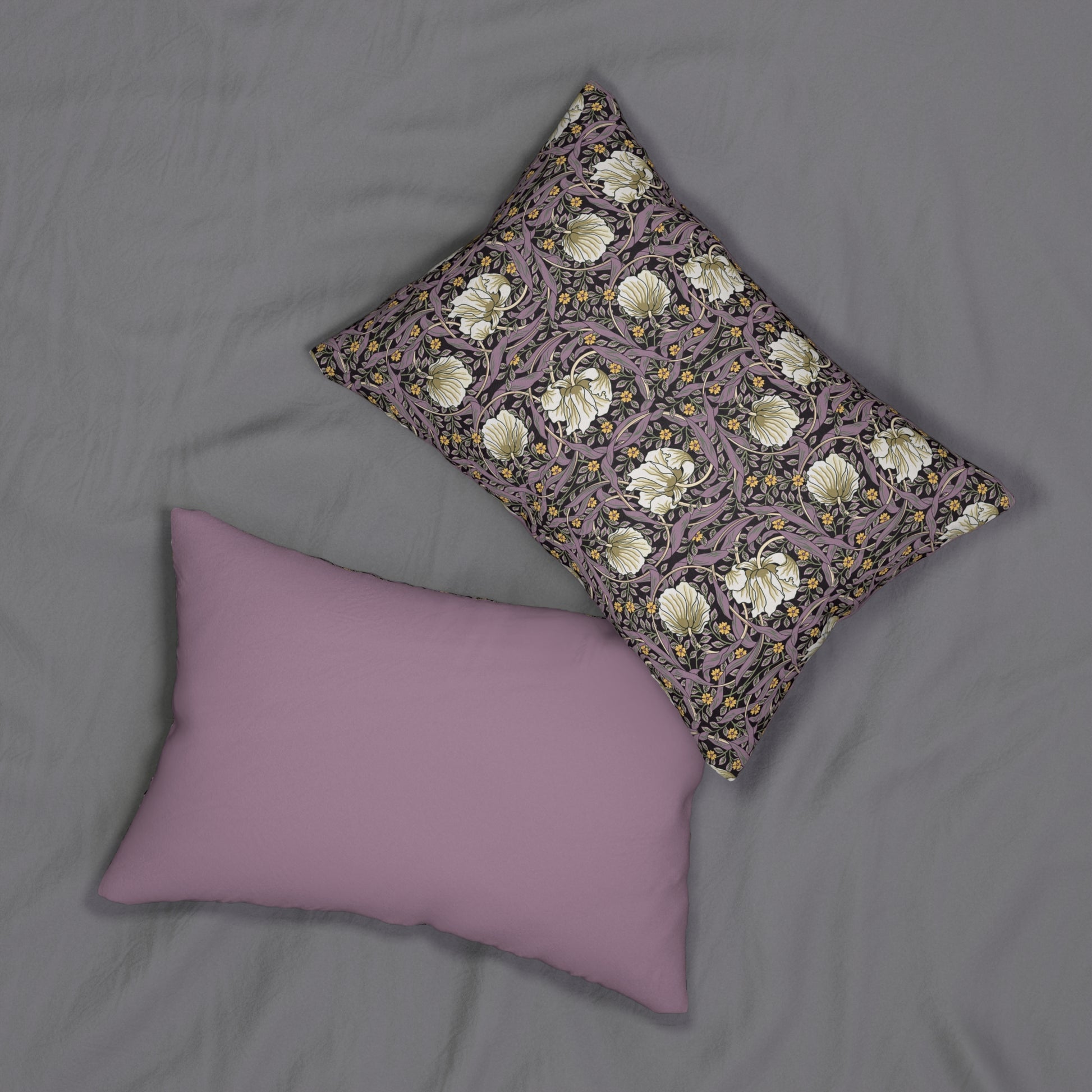 A rectangular lumbar cushion with a William Morris & Co floral pattern featuring pink and yellow flowers and green leaves on a dark background, with a concealed beige zipper.