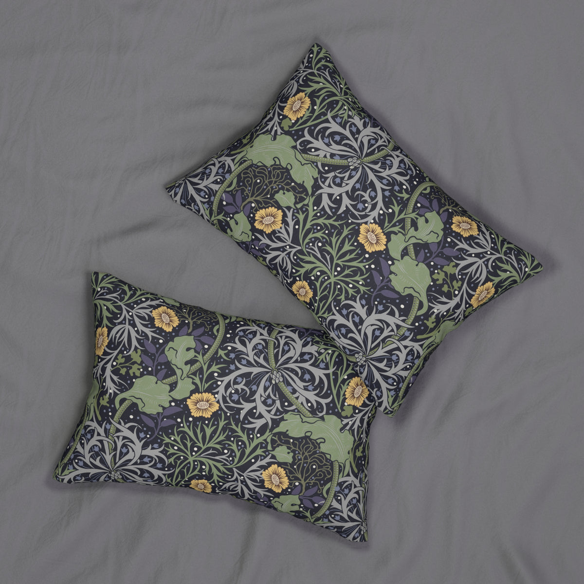 Two rectangular throw pillows with a William Morris-style floral and leaf pattern in muted green, gray, and yellow, displayed on a gray fabric background.