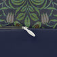 A rectangular lumbar cushion with a green and beige William Morris & Co floral pattern on a dark green background, featuring a concealed beige zipper.