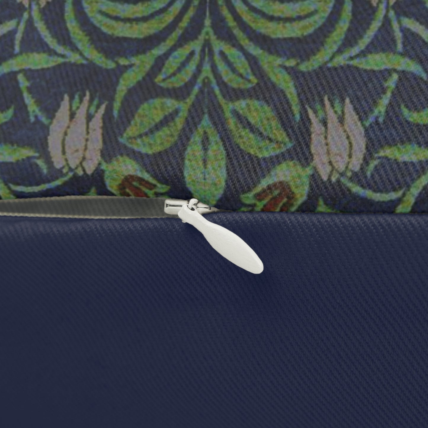 A rectangular lumbar cushion with a green and beige William Morris & Co floral pattern on a dark green background, featuring a concealed beige zipper.