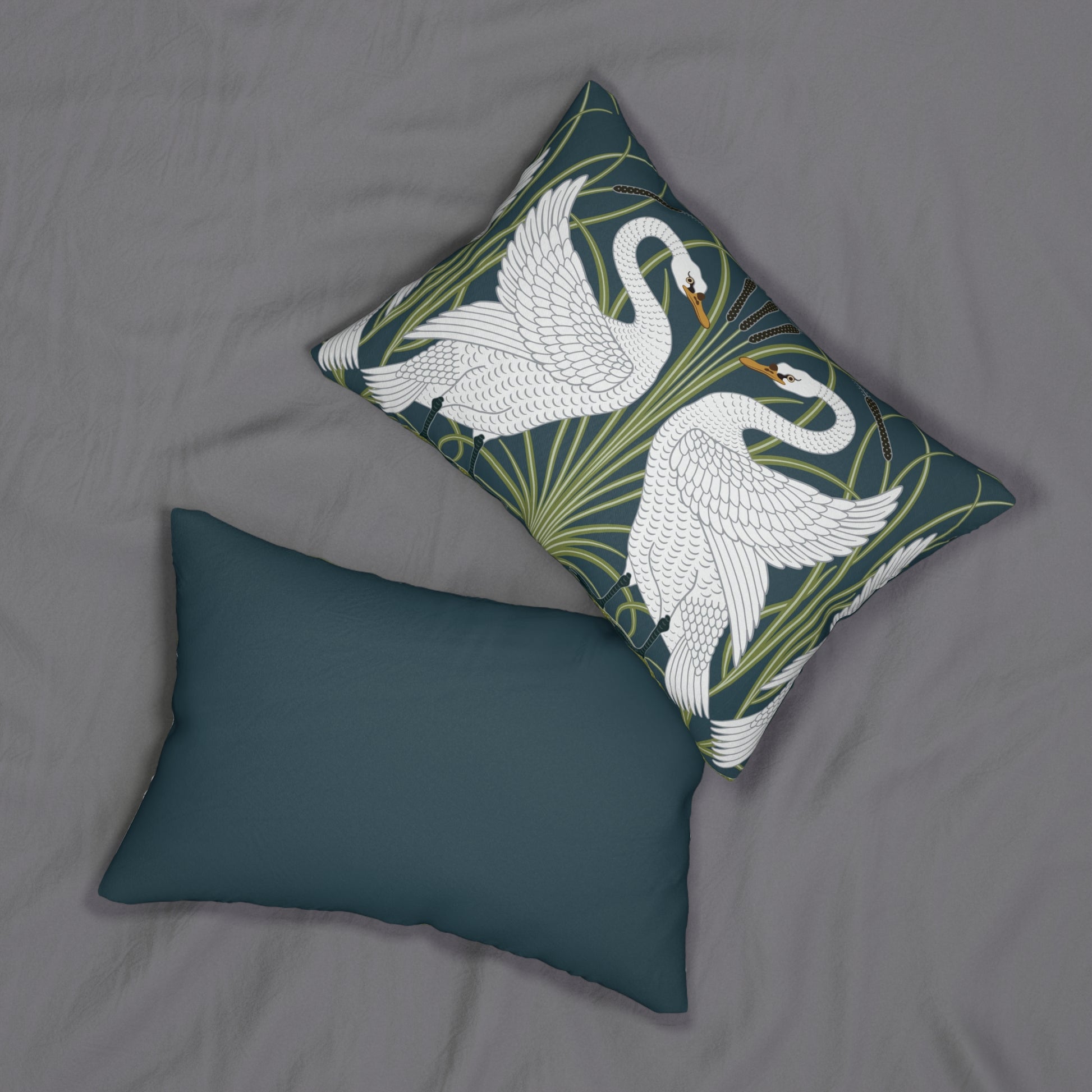 A decorative lumbar cushion featuring a white swan design on a darker background, with a floral William Morris & Co pattern in the background.