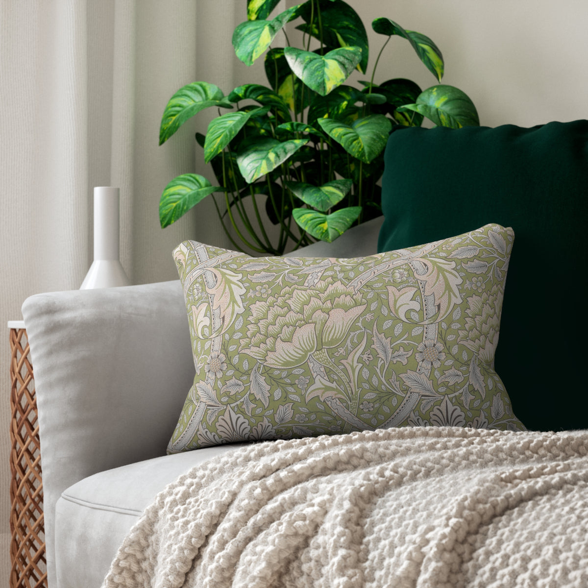 Decorative pillow with green and white pattern on a couch with a plant in the background