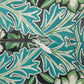 A close-up of a zipper on a fabric with a bold tropical leaf pattern in teal, green, and white.