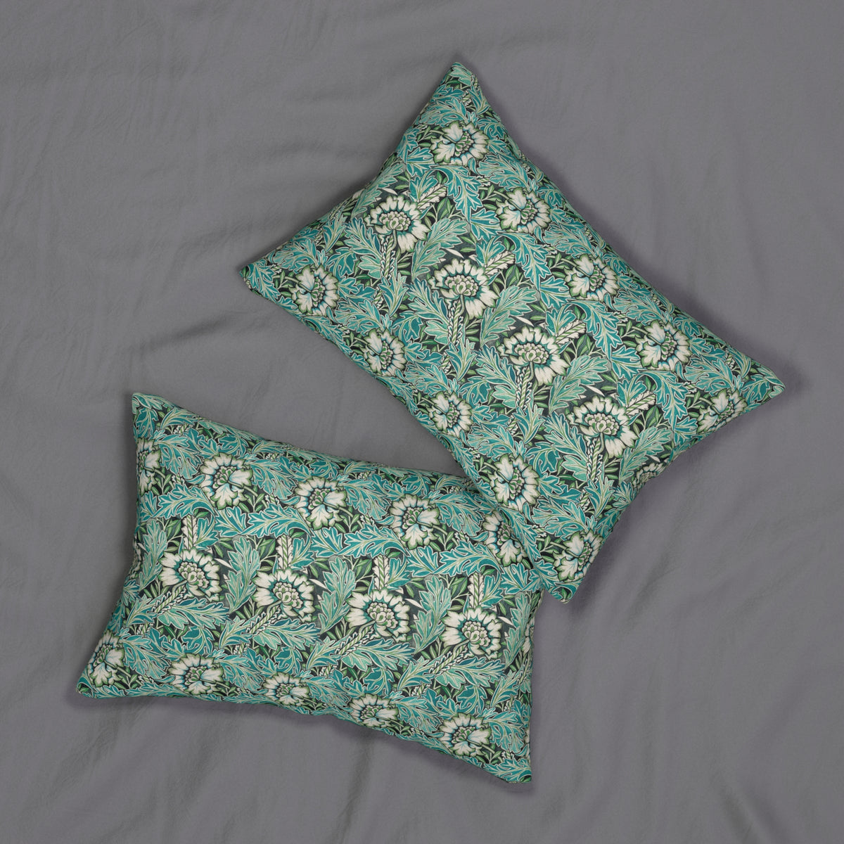 Two decorative throw pillows with a teal and white floral pattern, arranged on a gray fabric background.