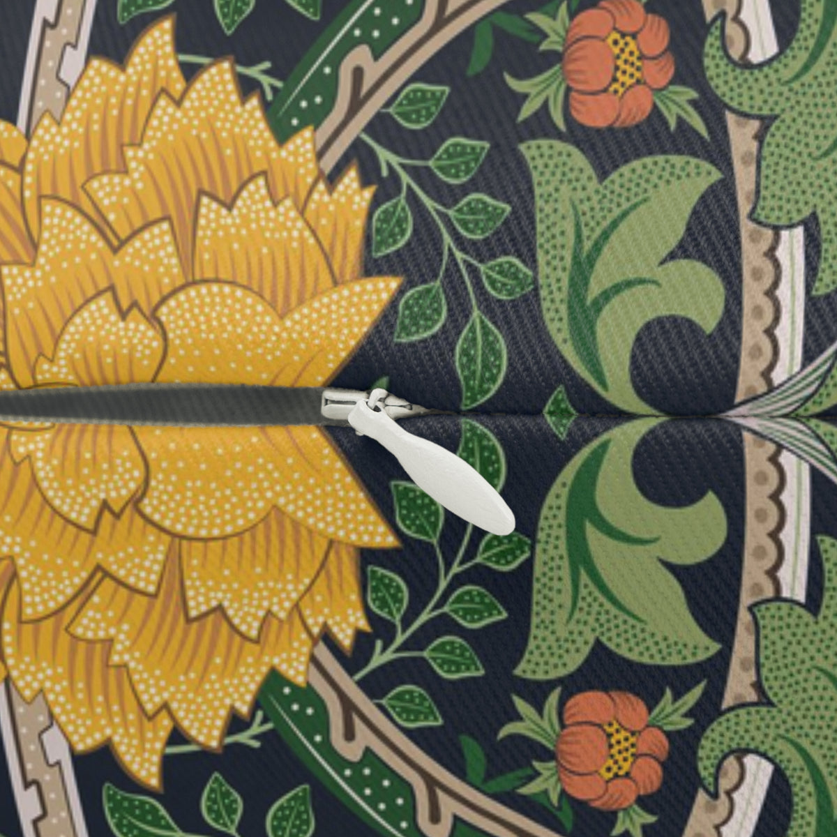 A close-up of a patterned fabric or wallpaper sample with a large yellow flower on the left, green leaves and vines across the center, and orange flowers on a dark navy background. A white plastic slider is visible horizontally across the middle, indicating a sample panel or swatch.