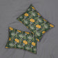 Two decorative throw pillows with a green and yellow floral pattern, arranged on a gray fabric background.