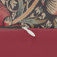 A rectangular lumbar cushion with a red and green William Morris & Co floral pattern on a textured background, featuring a concealed beige zipper.