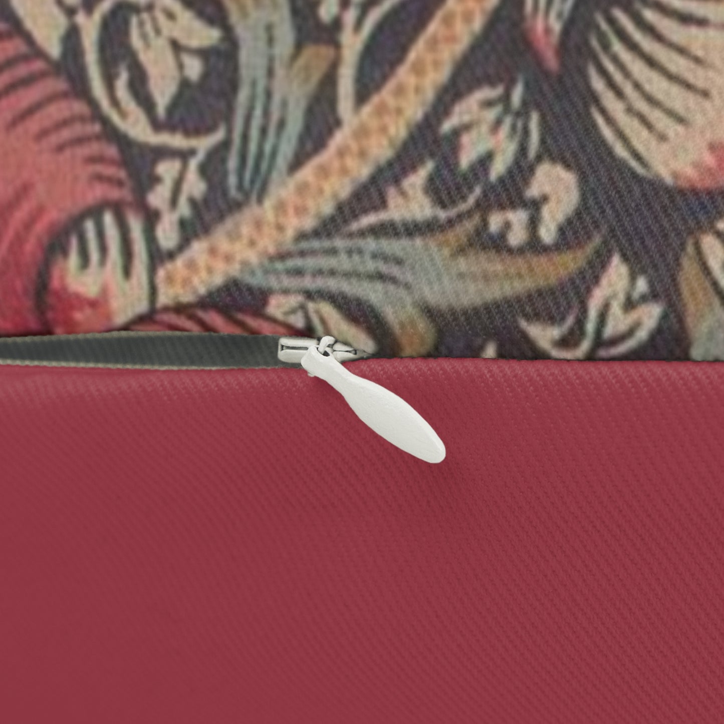 A rectangular lumbar cushion with a red and green William Morris & Co floral pattern on a textured background, featuring a concealed beige zipper.