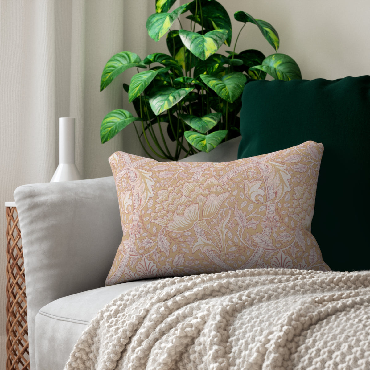 Pink patterned pillow on a gray sofa with a plant in the background