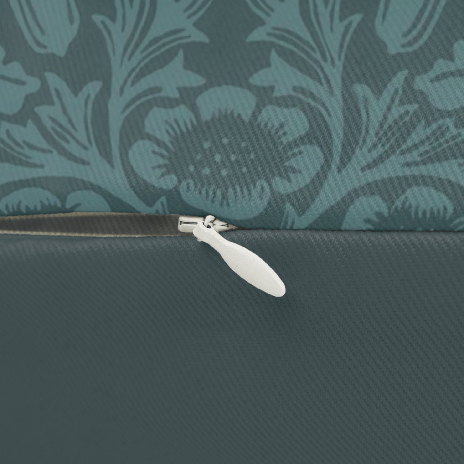 A rectangular lumbar cushion with a William Morris & Co floral pattern in teal colour, featuring acorn and oak leaves.