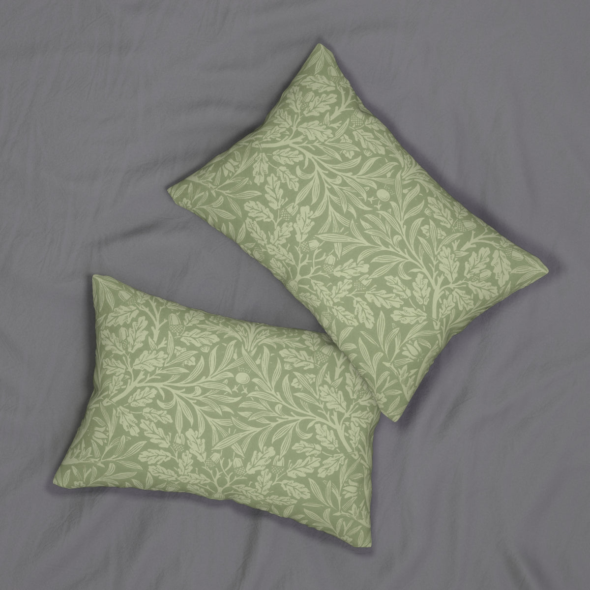 Two rectangular decorative throw pillows with a sage green and cream damask botanical pattern, arranged on a textured gray fabric background.