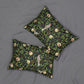 Two square decorative throw pillows with a dark green and black botanical pattern featuring pomegranate seeds, leaves, and birds, displayed on a gray fabric background.