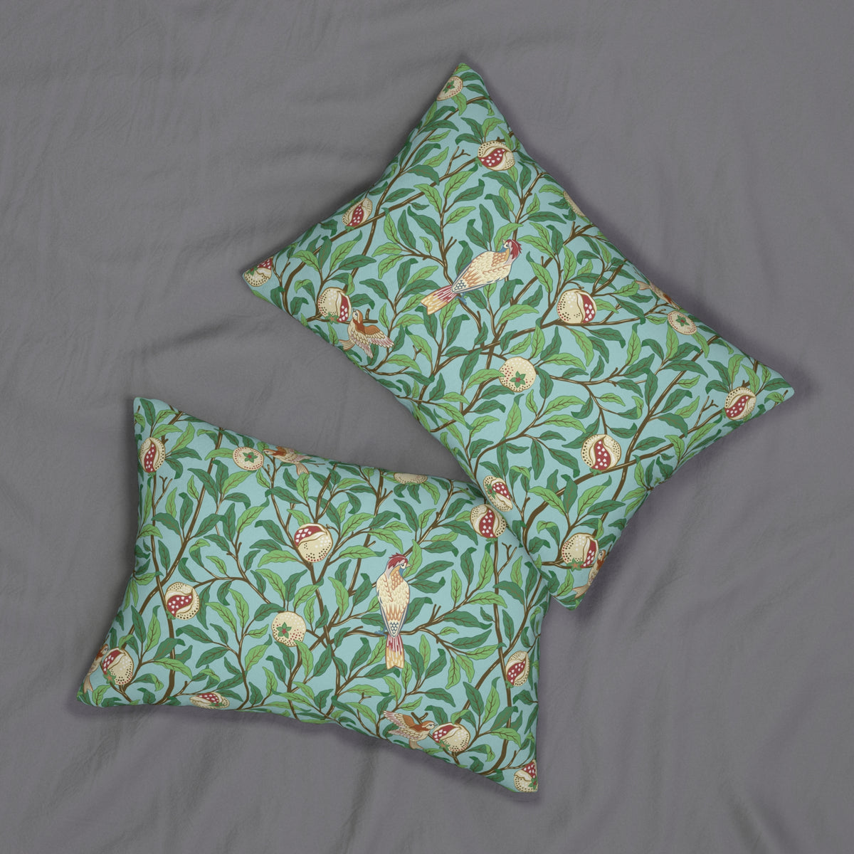 Two rectangular throw pillows with a green and blue botanical bird pattern, displayed on a gray fabric background.