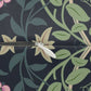 Close-up of a zipper with a white pull tab and silver metal teeth, set against a dark navy fabric printed with green leaves, beige flowers, and pink floral accents.