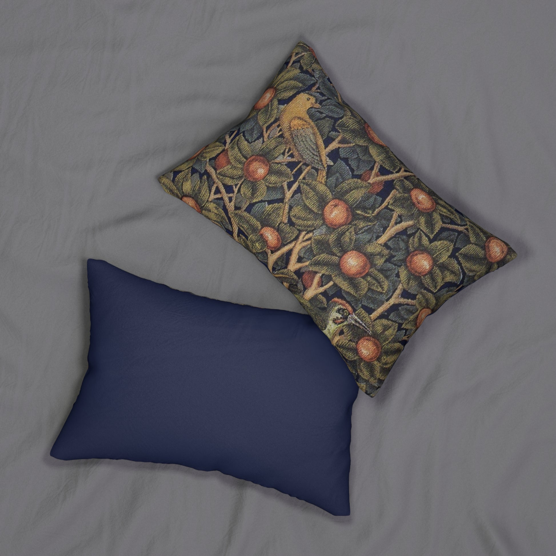 A rectangular lumbar cushion with an ornate design featuring birds, fruit, and leaves on a dark background, inspired by William Morris's art.