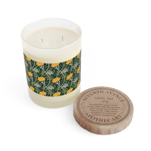 A yellow luxury scented candle with a floral patterned label, a clear glass jar, and a brown cardboard lid.