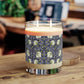 A clear candle with a lavender and sage William Morris & Co design called Pimpernel on the glass lid, alongside a brown cardboard lid with product information.