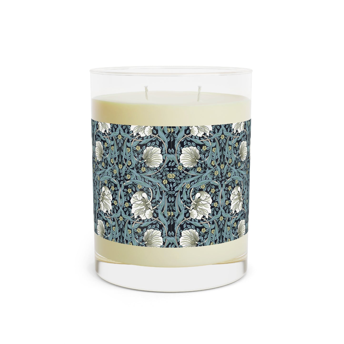 A clear glass candle with a William Morris & Co floral patterned lid and a label that reads 'Seventh Ave White Tea & Fig' alongside a brown cardboard lid.