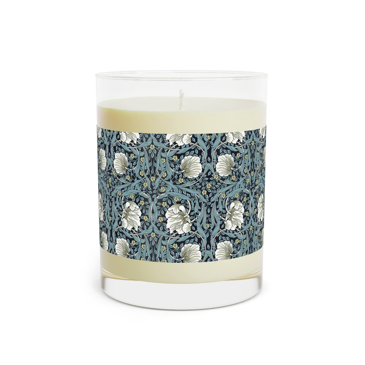 A clear glass candle with a William Morris & Co floral patterned lid and a label that reads 'Seventh Ave White Tea & Fig' alongside a brown cardboard lid.