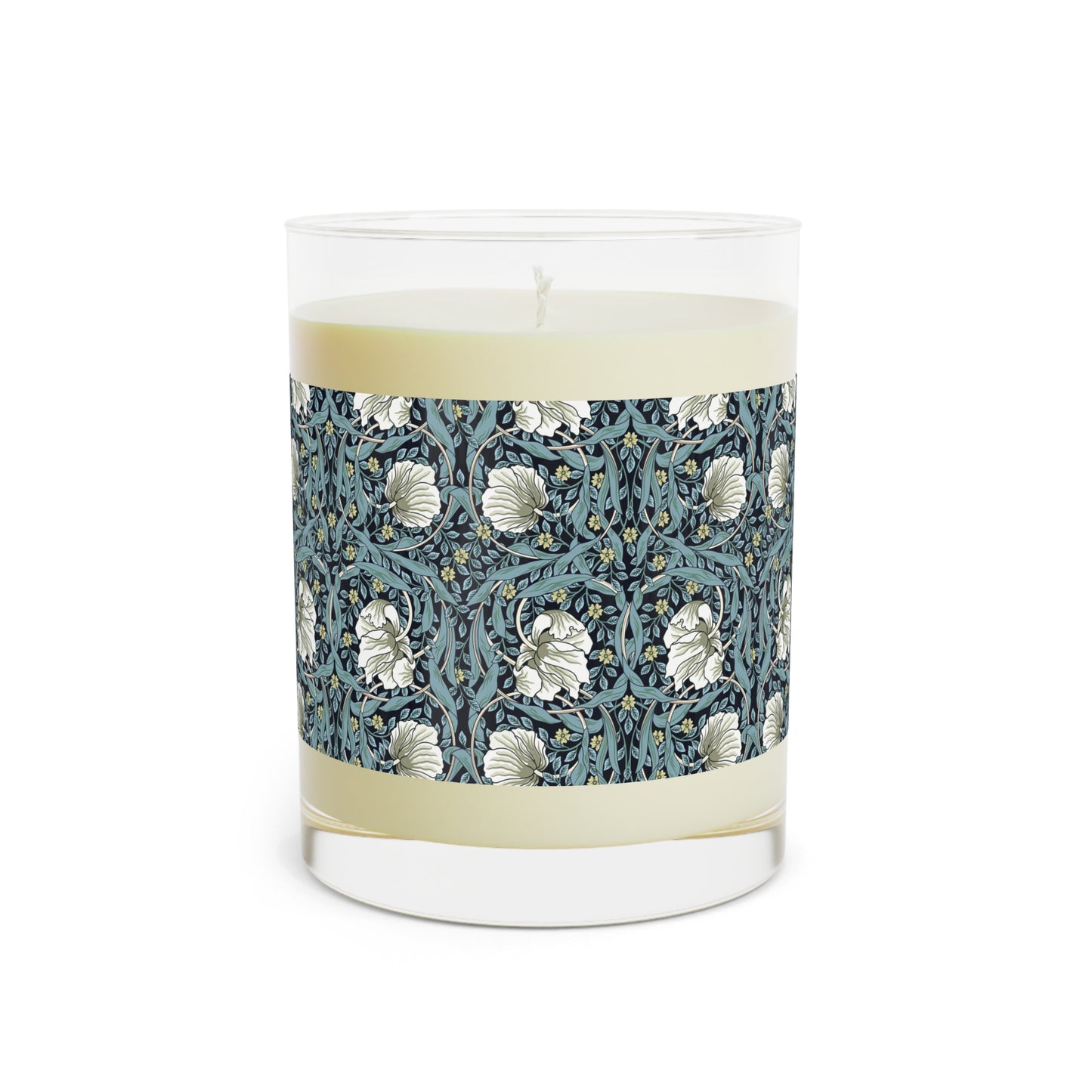 A clear glass candle with a William Morris & Co floral patterned lid and a label that reads 'Seventh Ave White Tea & Fig' alongside a brown cardboard lid.