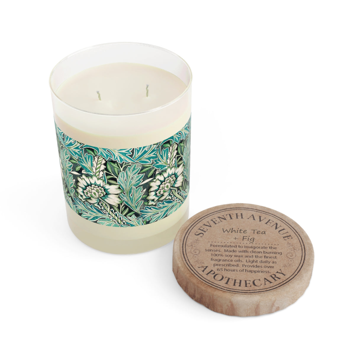 A two-wick scented candle in a clear glass vessel with a white wax body and a green botanical patterned label, shown next to its round wooden lid engraved with the brand name 'SUNTHAVENUE' and scent 'White Tea - Fig'.