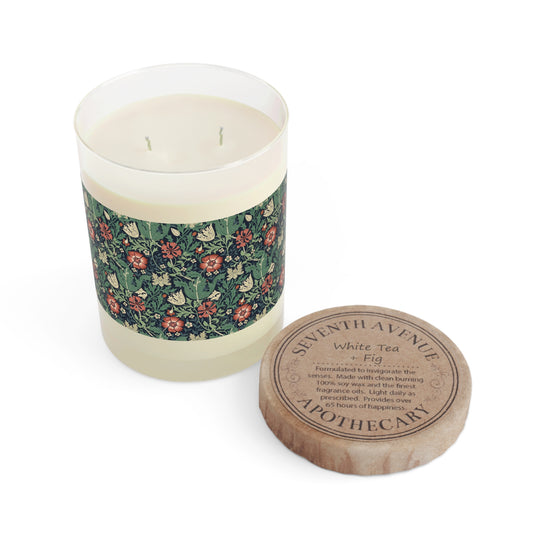A clear glass scented candle with a floral patterned label and a brown cardboard lid, labeled 'Seventh Avenue White Tea & Fig'.