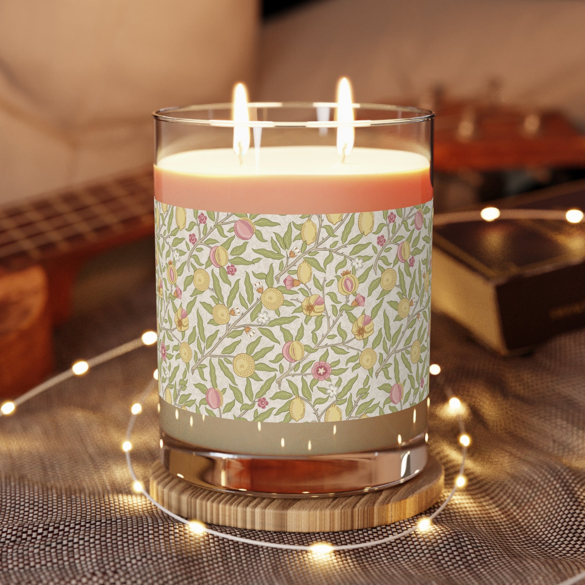 Candle with floral pattern on a wooden coaster with blurred background