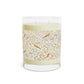Candle with decorative label featuring birds and floral patterns on a white background
