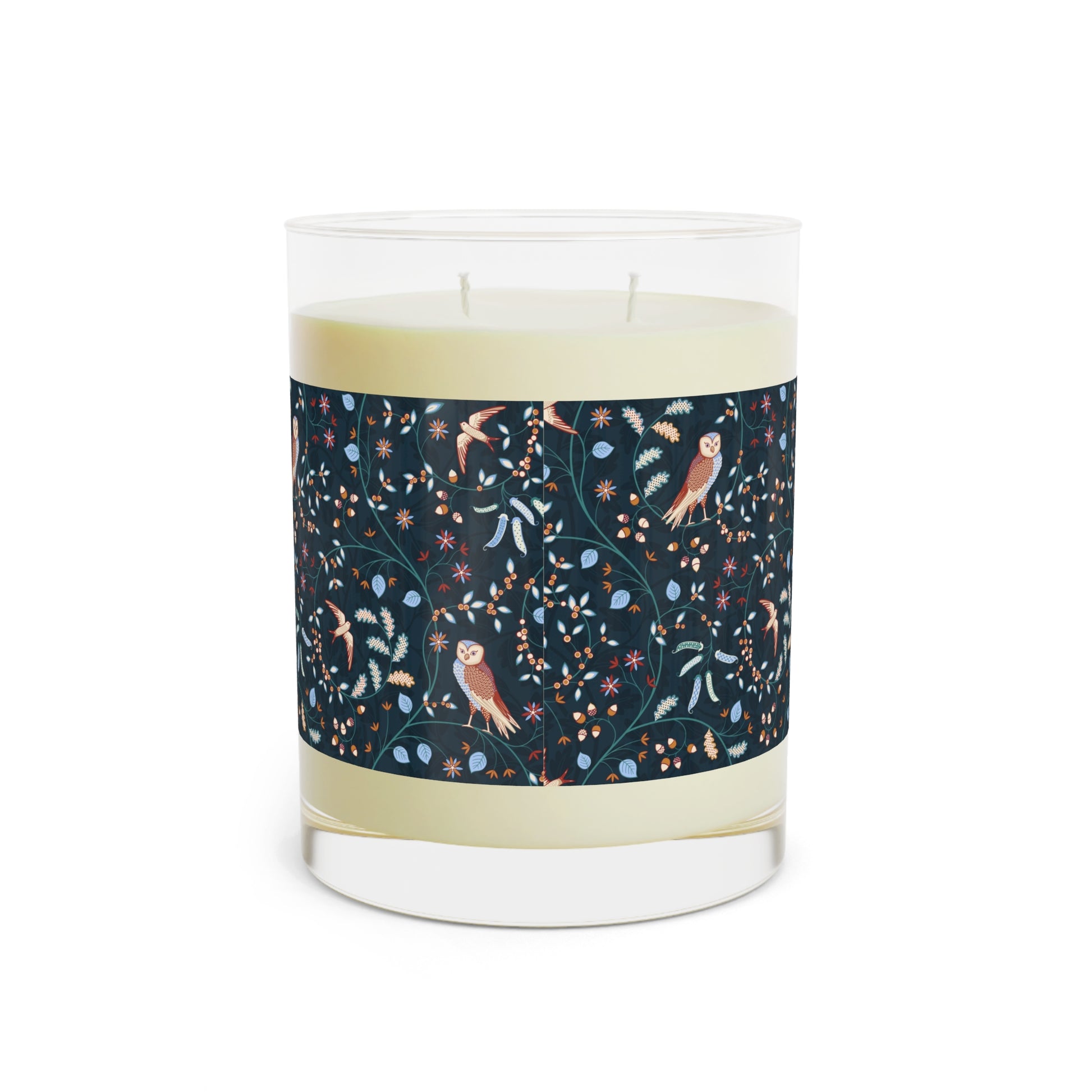 Candle with a decorative label featuring owls and plants on a white background
