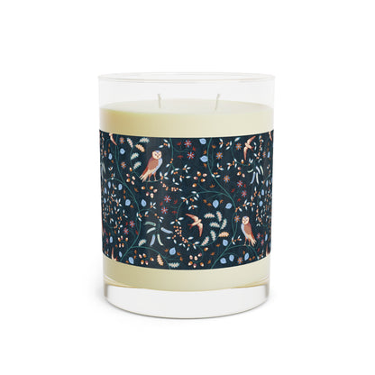 Candle with a decorative label featuring owls and plants on a white background