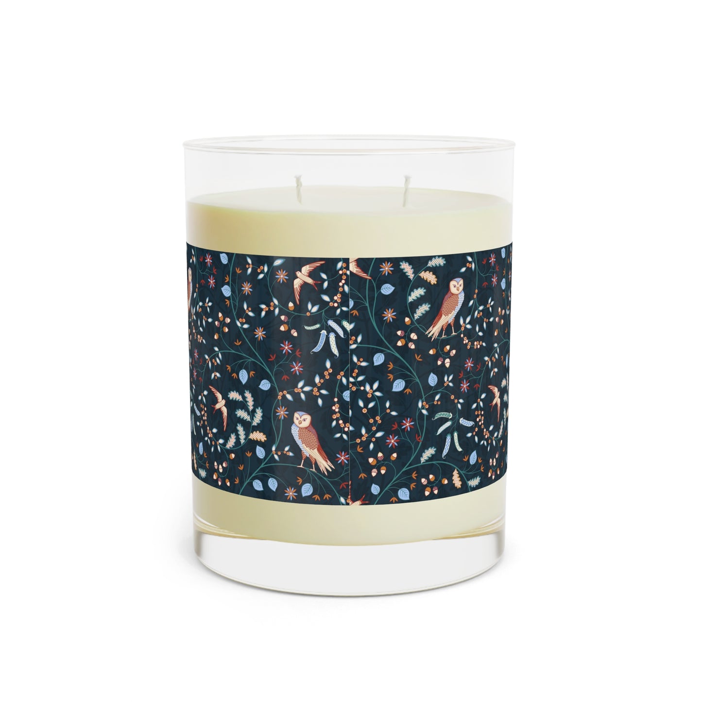 Candle with a decorative label featuring owls and plants on a white background