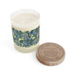 A William Morris & Co luxury scented candle in a glass jar with blue seaweed floral patterns, alongside a brown cardboard lid labeled 'White Tea & Fig'.